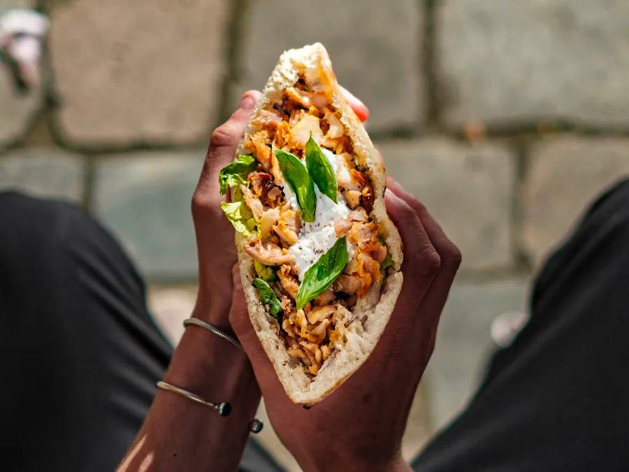 Sandwich artisanal Frau tenu à deux mains, garni de poulet et basilic